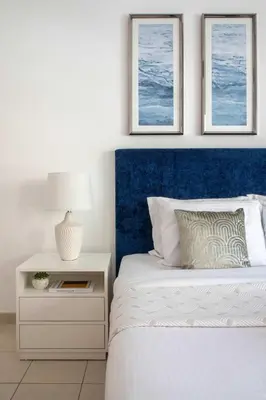 a bed with a blue headboard and a nightstand with a lamp at Frank Porter - Al Thayyal 2, The Greens in Dubai
