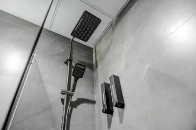 a shower in a bathroom with a stone wall at Great Gatsby's Home in Dubai