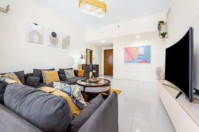 a living room with a gray couch and a flat screen tv at Great Gatsby's Home in Dubai