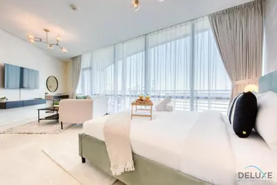 a bedroom with a large white bed and large windows at Upscale Studio at Sky Gardens DIFC by Deluxe Holiday Homes in Dubai