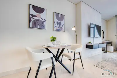 a dining room with a table and white chairs at Upscale Studio at Sky Gardens DIFC by Deluxe Holiday Homes in Dubai