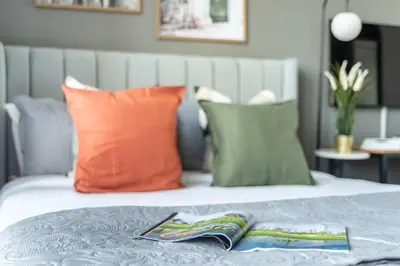 a bed with orange and green pillows and a book on it at Silkhaus Modern Burj Khalifa View Studio in Dubai