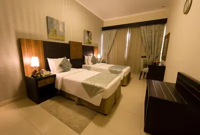 a hotel room with two beds and a window at Ivory Grand Hotel Apartments in Dubai