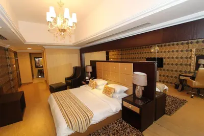 a bedroom with a large bed and a chandelier at Ivory Grand Hotel Apartments in Dubai