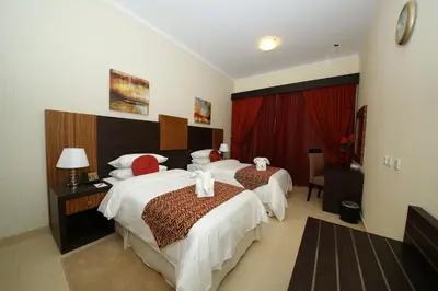 a hotel room with two beds and a red curtain at Ivory Grand Hotel Apartments in Dubai