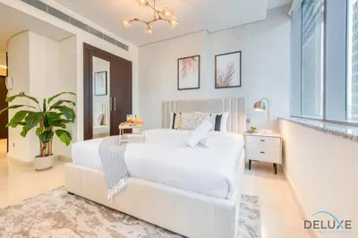 a white bedroom with a white bed and a plant at Sleek Studio at Sky Gardens DIFC by Deluxe Holiday Homes in Dubai