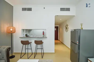 a kitchen with two bar stools and a refrigerator at Luxury Escapes - Modern Studio near Metro in X1 Tower JLT in Dubai
