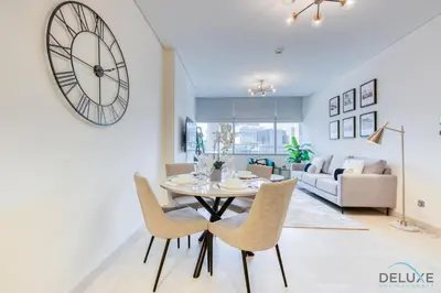 a dining room and living room with a clock on the wall at Best Deal Elegant Studio with Balcony & Prime Location by Deluxe Holiday Homes in Dubai