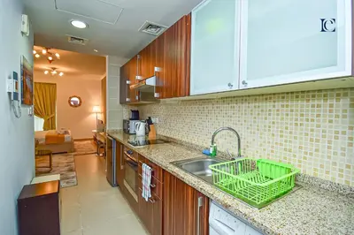 a kitchen with a sink and a green basket on the counter at Luxury Escapes - Cozy Studio - Goldcrest Executives JLT in Dubai