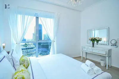 a white bedroom with a bed and a desk with a window at Luxury Escapes - Marina Views 1BR Apartments - Bay Central Dubai Marina in Dubai