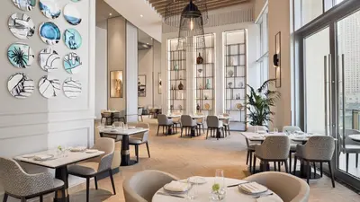a restaurant with tables and chairs and windows at Marina Mall Apartments, Dubai Marina in Dubai