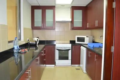 a kitchen with wooden cabinets and white appliances at Luxury Escapes - Large 1Bed with balcony and a great marina view in JBR in Dubai