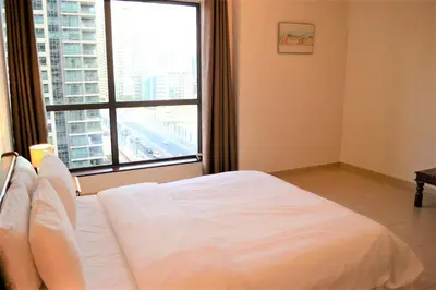 a white bed in a room with a large window at Luxury Escapes - Large 1Bed with balcony and a great marina view in JBR in Dubai
