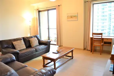 a living room with a leather couch and a coffee table at Luxury Escapes - Large 1Bed with balcony and a great marina view in JBR in Dubai