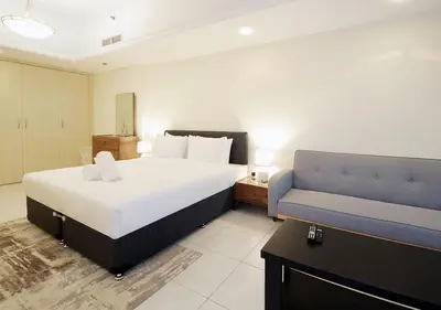 a bedroom with a large bed and a blue couch at RH- Cozy Studio, Al Waleed , Cluster R, JLT in Dubai