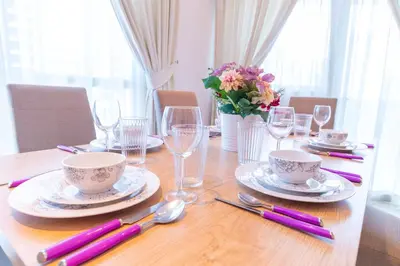 a wooden table with china plates and glasses on it at Luxury Escapes - Spacious 2BR Apt in the heart of Dubai Marina- Yacht Bay in Dubai