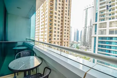 a balcony with two chairs and a table and a window at Luxury Escapes - Modern Studio Apt - Metro, Beach & Mall mins away in Dubai