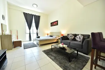 a living room with a couch and a table at Luxury Escapes - Spacious Fully Furnished Studio Apt - Next to Metro, 5 Mins from Mall - MED46 in Dubai