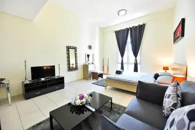 a living room with a couch and a tv at Luxury Escapes - Spacious Fully Furnished Studio Apt - Next to Metro, 5 Mins from Mall - MED46 in Dubai