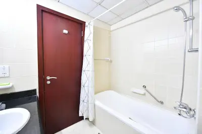 a bathroom with a white tub and a red door at Luxury Escapes - Spacious Fully Furnished Studio Apt - Next to Metro, 5 Mins from Mall - MED46 in Dubai