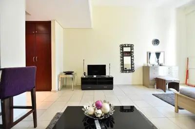 a living room with a couch and a tv at Luxury Escapes - Spacious Fully Furnished Studio Apt - Next to Metro, 5 Mins from Mall - MED46 in Dubai