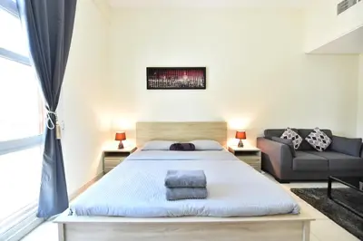 a bedroom with a large bed and a couch at Luxury Escapes - Spacious Fully Furnished Studio Apt - Next to Metro, 5 Mins from Mall - MED46 in Dubai