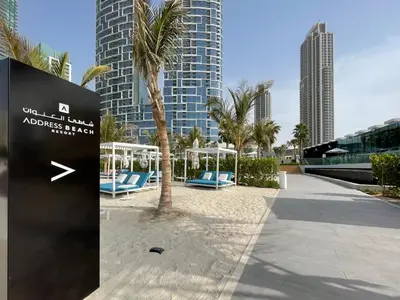 a sign on a beach with palm trees and buildings at The Smart Concierge - Address JBR in Dubai