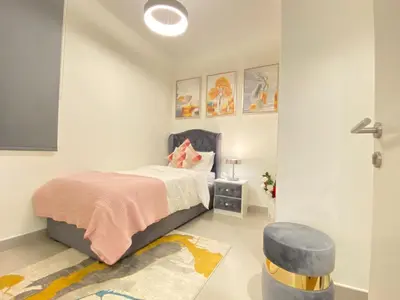 a small bedroom with a bed and a stool at Modern Dubai Hills Luxury 4 BEDROOM VILLA in Dubai