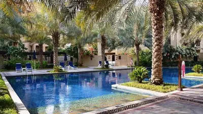 a large swimming pool with palm trees and chairs at Trophy 2BR Aladdin Estate w Burj Khalifa View in Dubai