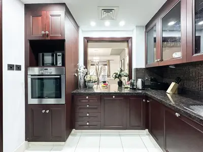 a kitchen with brown cabinets and a counter top at Trophy 2BR Aladdin Estate w Burj Khalifa View in Dubai