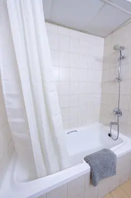 a bathtub with a shower curtain in a bathroom at Luxury Escapes - Budget Studio Apt near Metro Stn - MOG184 DG in Dubai