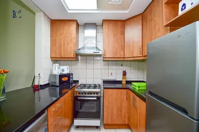 a kitchen with wooden cabinets and a stainless steel refrigerator at Luxury Escapes - Cozy budget studio near Metro & Ibn Battuta Mall - MOG190 DG in Dubai