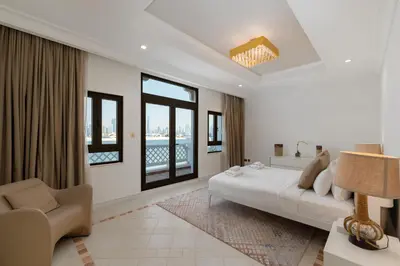 a bedroom with a bed and a couch and windows at Palm Jumeirah - Property Advisers in Dubai