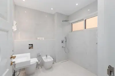a white bathroom with a toilet and a sink at Palm Jumeirah - Property Advisers in Dubai