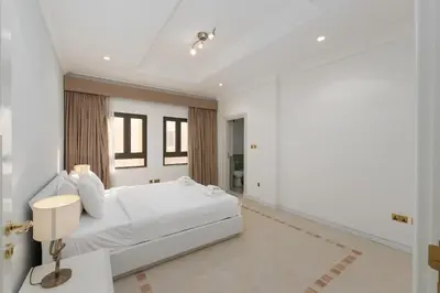 a white bedroom with a large white bed and windows at Palm Jumeirah - Property Advisers in Dubai