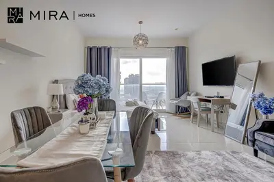 a living room with a table and chairs and a television at Mira Holiday Homes - Lovely Studio in AG tower with free parking in Dubai