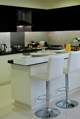 a kitchen with a white counter and two bar stools at DAMAC Maison Mall Street in Dubai