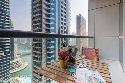 a table with wine glasses and flowers on a balcony at Frank Porter - Bay Central in Dubai