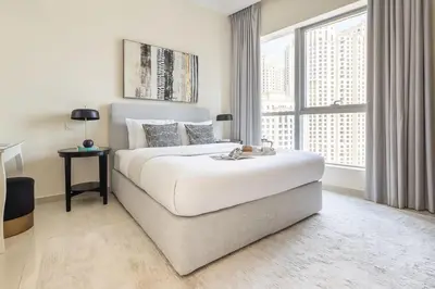 a white bedroom with a large bed and a large window at Frank Porter - Bay Central in Dubai