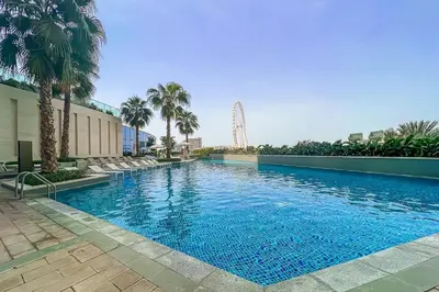 a large swimming pool with palm trees and a ferris wheel at Frank Porter - The Address JBR in Dubai