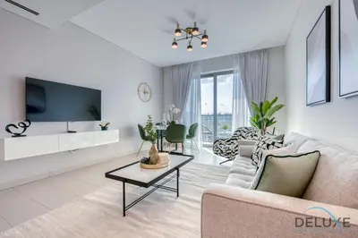 a living room with a couch and a tv at Notable 2BR at Sobha Hartland Greens MBR City by Deluxe Holiday Homes in Dubai