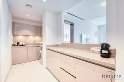 a kitchen with white cabinets and a dishwasher at Notable 2BR at Sobha Hartland Greens MBR City by Deluxe Holiday Homes in Dubai