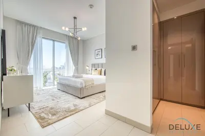 a bedroom with a bed and a large window at Notable 2BR at Sobha Hartland Greens MBR City by Deluxe Holiday Homes in Dubai