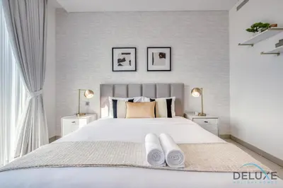 a bedroom with a large white bed with two lamps at Notable 2BR at Sobha Hartland Greens MBR City by Deluxe Holiday Homes in Dubai