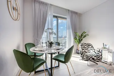 a dining room with a table and green chairs at Notable 2BR at Sobha Hartland Greens MBR City by Deluxe Holiday Homes in Dubai
