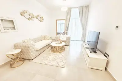 a living room with a couch and a tv at Modern 1BR in Jumeirah Village Circle (Pool View) in Dubai