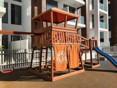 a playground with a swing and a slide at Modern 1BR in Jumeirah Village Circle (Pool View) in Dubai
