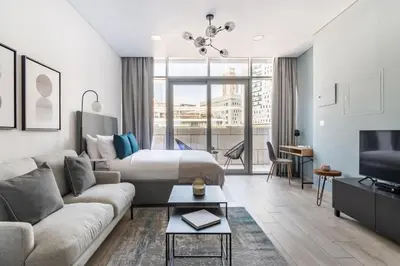 a hotel room with a bed and a couch and a tv at Silkhaus elegant studio in the central DIFC with balcony and city views in Dubai