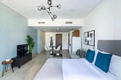 a bedroom with a white bed and a living room at Silkhaus elegant studio in the central DIFC with balcony and city views in Dubai