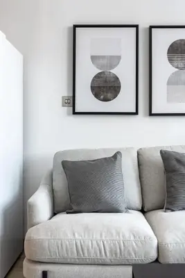 a living room with a couch and two framed pictures at Silkhaus elegant studio in the central DIFC with balcony and city views in Dubai